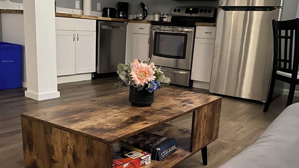A modern kitchen with white cabinets, stainless steel appliances, and a wooden coffee table with a flower vase. - Your private suite awaits.Half a block from Gryro park. Quite safe area! (Trail)
