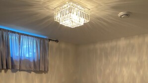 A neatly made bed with white linens, a dark headboard, and a chandelier above. - Your private suite awaits.Half a block from Gryro park. Quite safe area! (Trail)