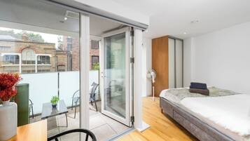 Une chambre moderne avec un lit, un bureau et une porte-fenêtre coulissante donnant sur un balcon.