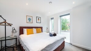 A modern hotel room with a large bed, a wardrobe, a bedside table, and a window with a view. - Shoreditch | 3 King Beds | Fast Wi-Fi | Balcony (London)