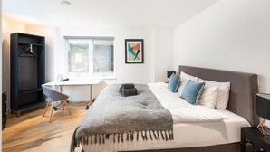 A bedroom with a bed, a desk, a chair, a wardrobe, and a window. - Shoreditch | 3 King Beds | Fast Wi-Fi | Balcony (London)