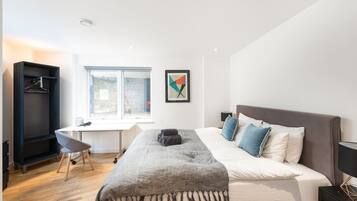 Une chambre à coucher avec un lit, un bureau, une chaise, une armoire et une fenêtre.
