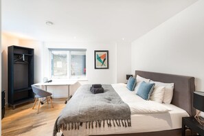 A bedroom with a bed, a desk, a chair, a wardrobe, and a window. - Shoreditch | 3 King Beds | Fast Wi-Fi | Balcony (London)