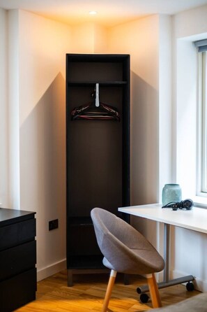 Una habitación compacta con armario empotrado, un escritorio con silla y ventana.