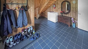 A room with a wooden staircase, a white refrigerator, a mirror, and a shoe rack with various types of footwear. - Awesome home in Kongshus with sauna (Kongshus)