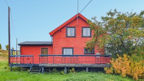 Ett rött trähus med en veranda och en liten ytterdörr.