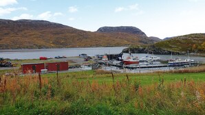 En hamn med båtar, en röd byggnad och en bergig bakgrund.