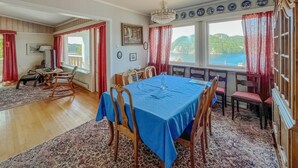 A dining area with a blue tablecloth, wooden chairs, and a view of the sea through large windows. - 3 bedroom amazing home in Farsund (Farsund)