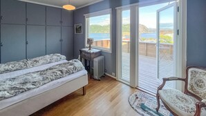 A bedroom with a bed, a dresser, a radiator, and a chair. There are two windows and a view of the outdoors. - 3 bedroom amazing home in Farsund (Farsund)