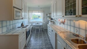 A narrow kitchen with white cabinets, a dining table with chairs, and a view of the outdoors through a window. - 3 bedroom amazing home in Farsund (Farsund)