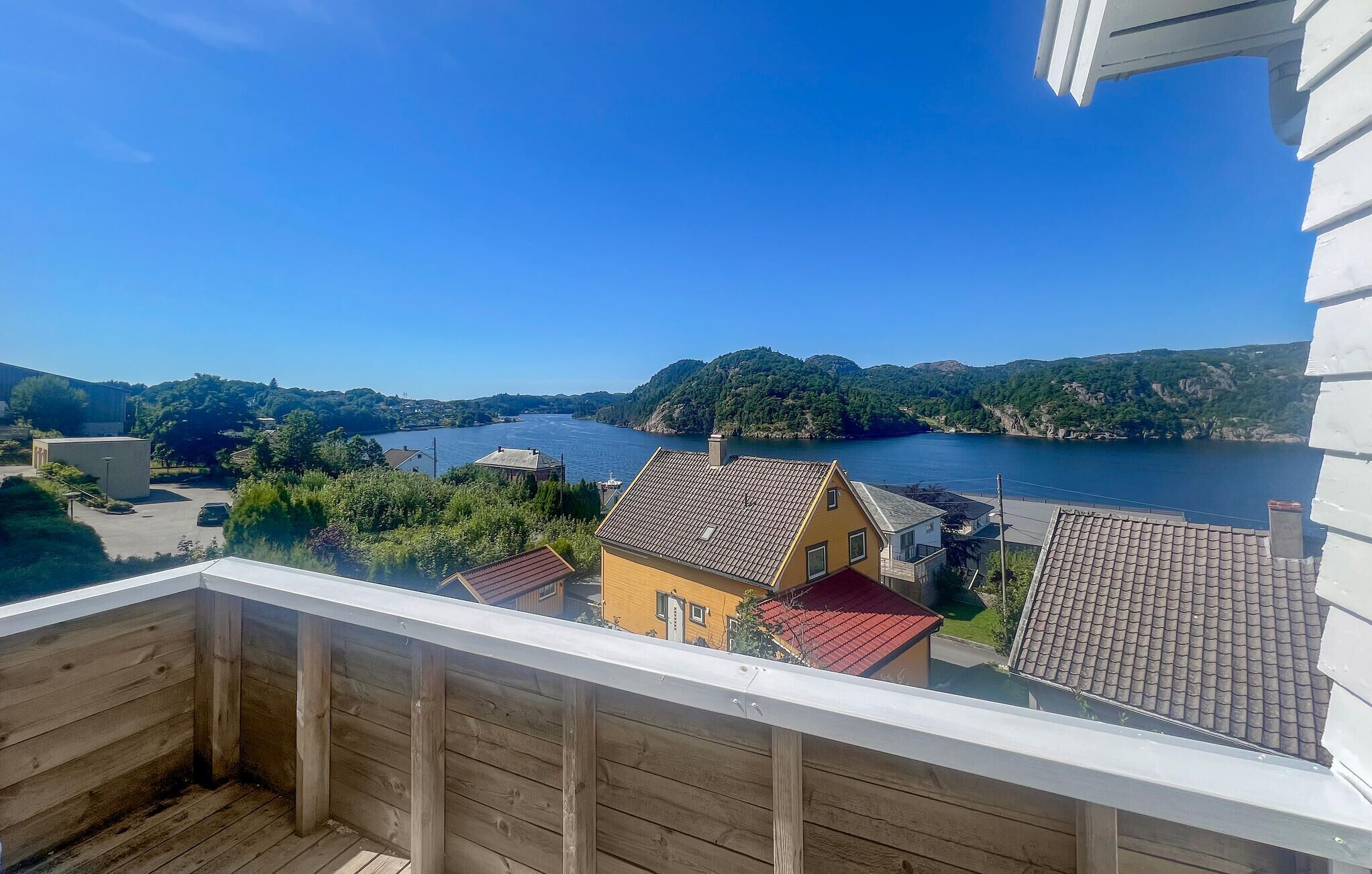 Un balcon donnant sur un lac, entouré de maisons et de verdure.