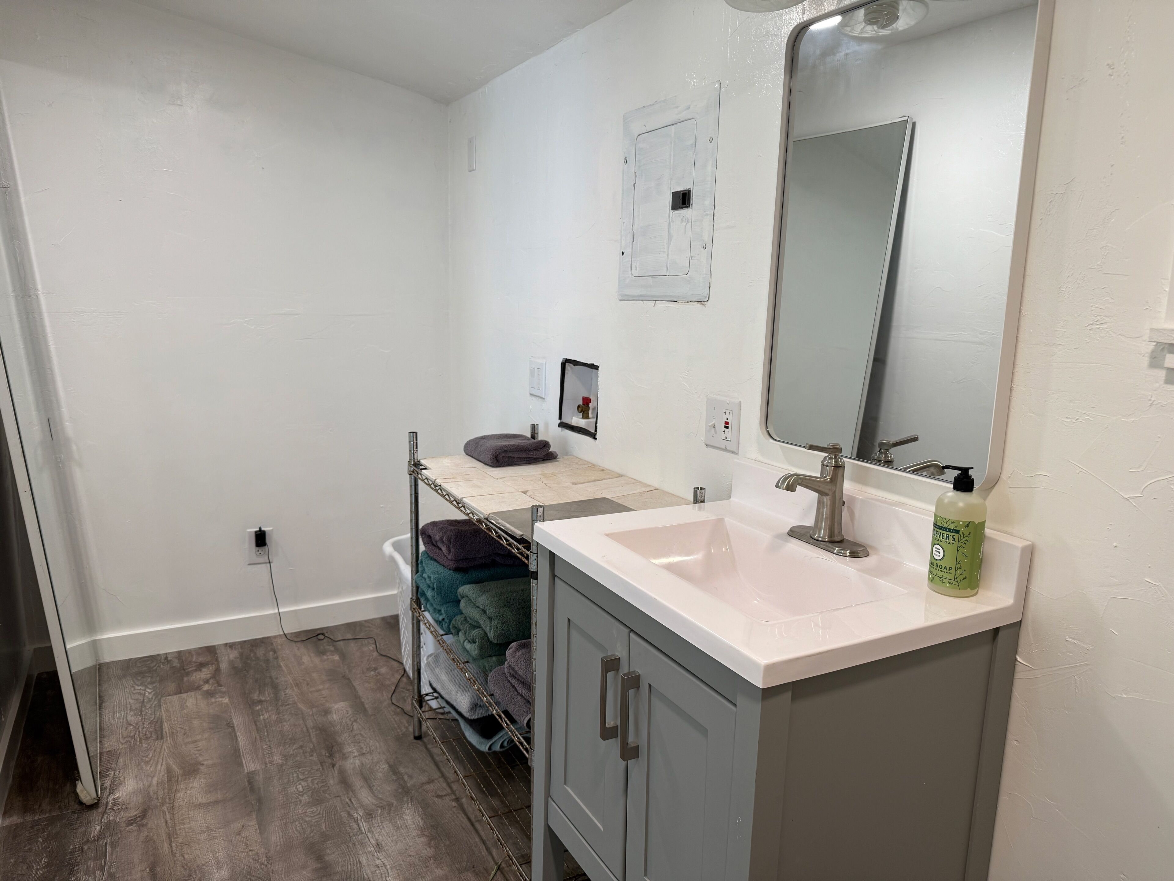 A bathroom with a white sink, a mirror, a towel rack, and a shower area.