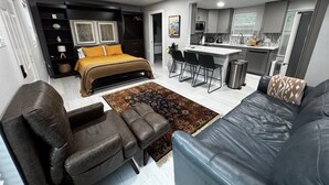 Un appartement moderne comprenant un lit, un canapé, des fauteuils, une petite cuisine et un coin repas.