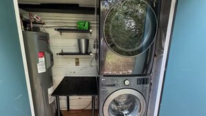 Une petite buanderie comprenant un lave-linge et un sèche-linge, une petite table et un chauffe-eau.
