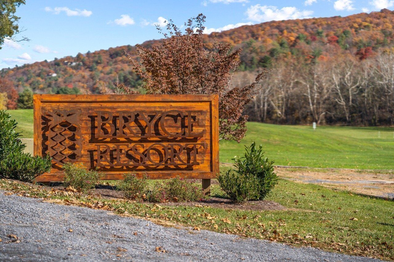 Une enseigne en bois indiquant le nom de Bryce Canyon Resort, avec une chaîne de montagnes en arrière-plan.