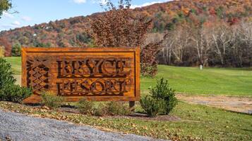 Une enseigne en bois indiquant le nom de Bryce Canyon Resort, avec une chaîne de montagnes en arrière-plan.