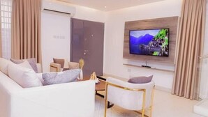 A modern living room with a sofa, armchair, and a TV mounted on the wall. - Harmony Heights (Tema)