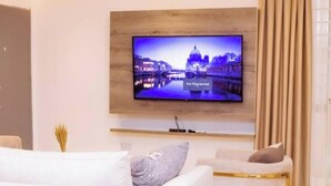 Una sala de estar moderna con un televisor de pantalla plana montado en la pared que muestra un paisaje urbano.