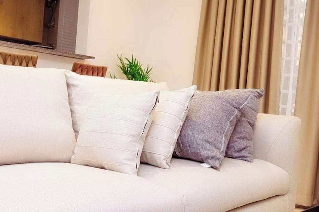 A white sofa with three pillows in a living room.