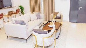 Un salon moderne comprenant un canapé, des fauteuils, une table basse et un coin repas avec des chaises.
