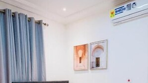 A bedroom with a bed, nightstand, and wall-mounted air conditioner. - Solace Villa (Tema)