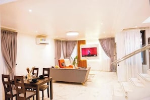 Ein modernes Wohnzimmer mit Essbereich, einer Couch und einem an der Wand montierten Fernseher.