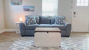 A living room with a gray sofa, patterned cushions, a wooden coffee table, and a decorative rug.