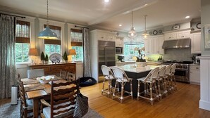 A spacious kitchen with a central island, wooden dining table, and chairs. -  Sophisticated Stay in heart of Five Points-Walk to the action, Relax in luxury. (Athens)