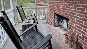 A covered porch with a brick fireplace, wooden benches, and a view of a garden. -  Sophisticated Stay in heart of Five Points-Walk to the action, Relax in luxury. (Athens)