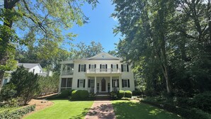 A two-story house with a front porch, surrounded by trees and a well-maintained lawn. -  Sophisticated Stay in heart of Five Points-Walk to the action, Relax in luxury. (Athens)