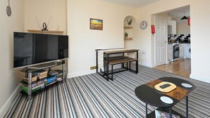 Un salon avec un téléviseur, des livres, une table basse et un tapis à rayures.