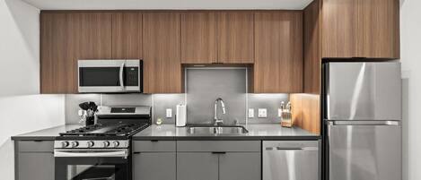 Una cocina moderna con electrodomésticos de acero inoxidable, horno integrado y armarios de madera.