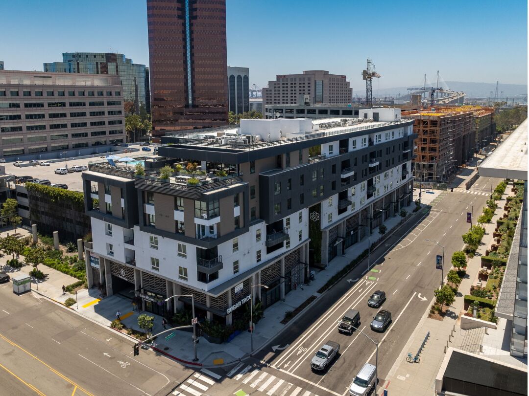 A modern multi-story building with a flat roof, large windows, and a ground-level commercial space.