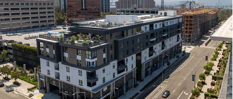 A modern multi-story building with a flat roof, large windows, and a ground-level commercial space.