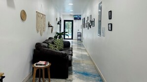 A hallway with a black leather sofa, a small wooden stool, and a potted plant. - The Ranch Jamaica Eco Resort and Ranch (St. Catherine Parish)
