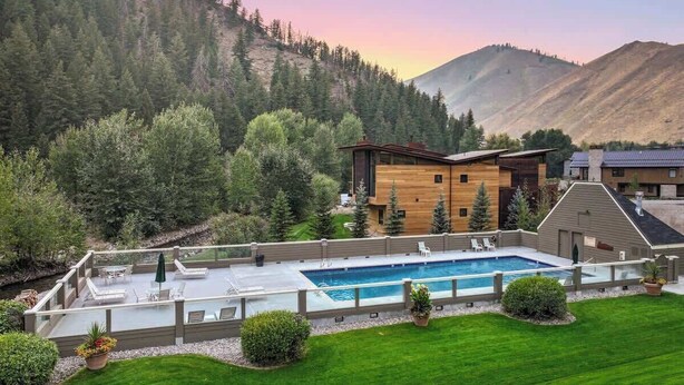 A modern house with a swimming pool, surrounded by a well-maintained lawn and trees.
