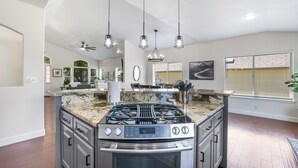 A modern kitchen with a central island, stainless steel appliances, and pendant lighting.