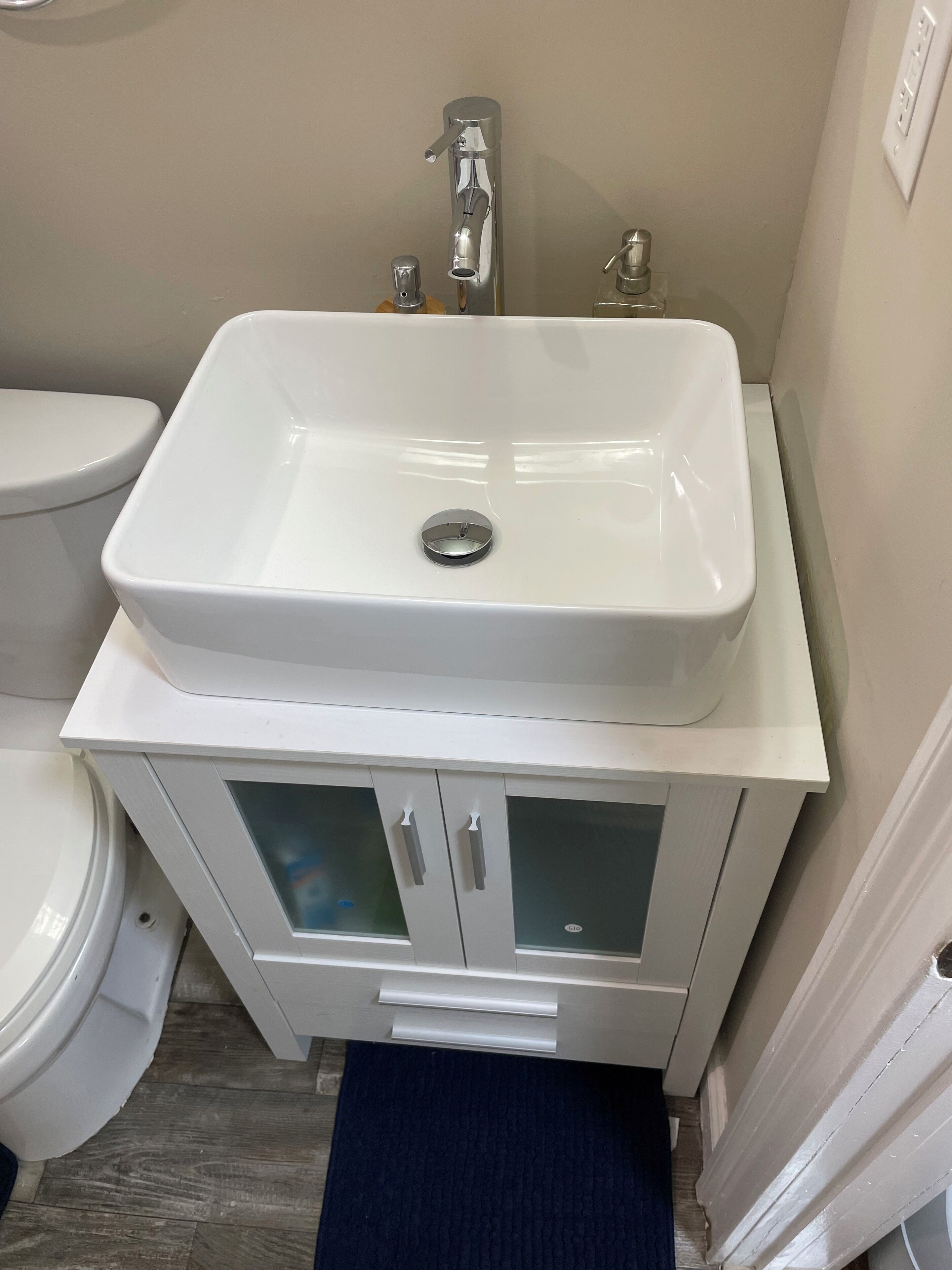 Een badkamer met een witte wastafel, toilet en een kast met glazen deuren.