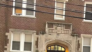 A black car parked in front of a brick building with a large arched entrance and multiple windows. - AC’s Finest! (Atlantic City)