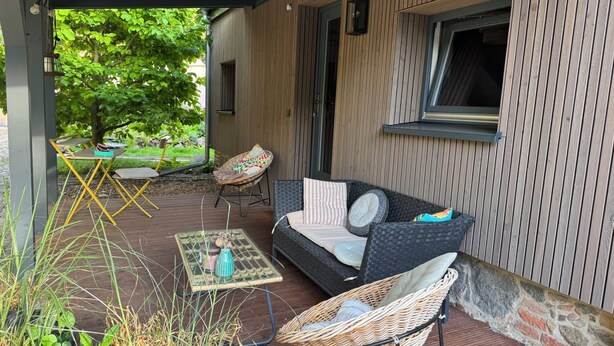 An outdoor patio with a wicker sofa, a small table, and a chair.