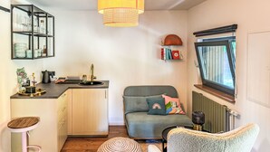 A compact living space with a kitchenette, a dining area, and a cozy seating area with a window.