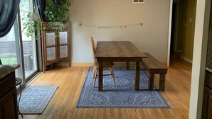 Een eetgedeelte met een houten tafel en bank, een plafondventilator en een hangplant.