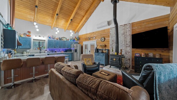 A cozy living room with a fireplace, a kitchen with blue cabinets, and a bar area.
