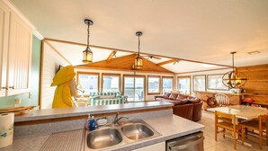 A spacious kitchen with a large island, wooden ceiling beams, and a view of the outside.