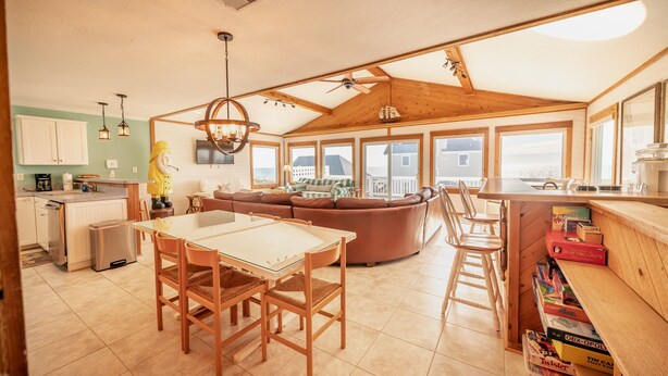 A spacious kitchen with a dining area, a wooden ceiling, and large windows offering views of the surrounding area.