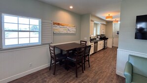 A spacious kitchen with a dining area, wooden flooring, and a large window. - Pet Friendly, Close to the Beach, Golf Cart Access (Port Aransas)
