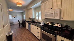 A kitchen with white cabinets, a black countertop, stainless steel appliances, and a wooden floor. - Pet Friendly, Close to the Beach, Golf Cart Access (Port Aransas)