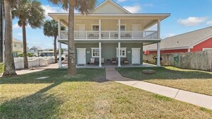 A two-story house with a balcony, a front porch, and a small front yard. - Pet Friendly, Close to the Beach, Golf Cart Access (Port Aransas)