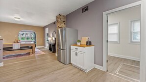 A modern kitchen with a stainless steel refrigerator, a wooden cabinet, and a stone accent wall. - Brady St Retreat Front House - Sleeps 8 & Pets (Milwaukee)