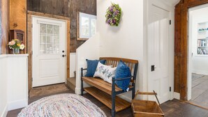 A wooden bench with blue cushions in a hallway with a white door and a wooden wall. - Historic Gem in Virginia City (Virginia City)